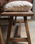 Oak bench side view with cream cushion on top.