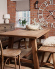 Oak dining set with table and bench, styled with bobble bowl and large clock in background.