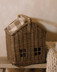 Woven basket with handle with chunky knitted throw on wooden bench.