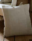 Close up of striped cream cushion leaning on wooden armchair.
