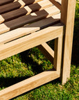 Wooden outdoor bench with brown and beige slats on a grassy background