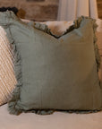 Large green ruffle linen cushion on cream sofa.