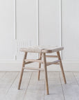 Lulworth Rustic Wooden Stool against a white panelled wall an wooden floor.