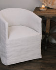Natural linen dining chair with rounded back on wooden floor next to wooden table.