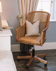 Natural rattan wicker office chair with neutral cushion at white desk.