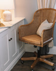 Natural rattan wicker office chair with neutral cushion at white desk.