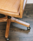 Natural rattan wicker office chair with neutral cushion at white desk.