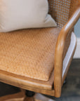Natural rattan wicker office chair with neutral cushion at white desk.