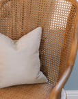 Natural rattan wicker office chair with neutral cushion at white desk.