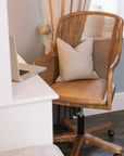 Natural rattan wicker office chair with neutral cushion at white desk with laptop.
