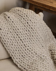 Chunky knitted blanket thrown over an armchair.