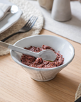 Patrycja Serving Bowl with Spoon on wooden table with tomato sauce.
