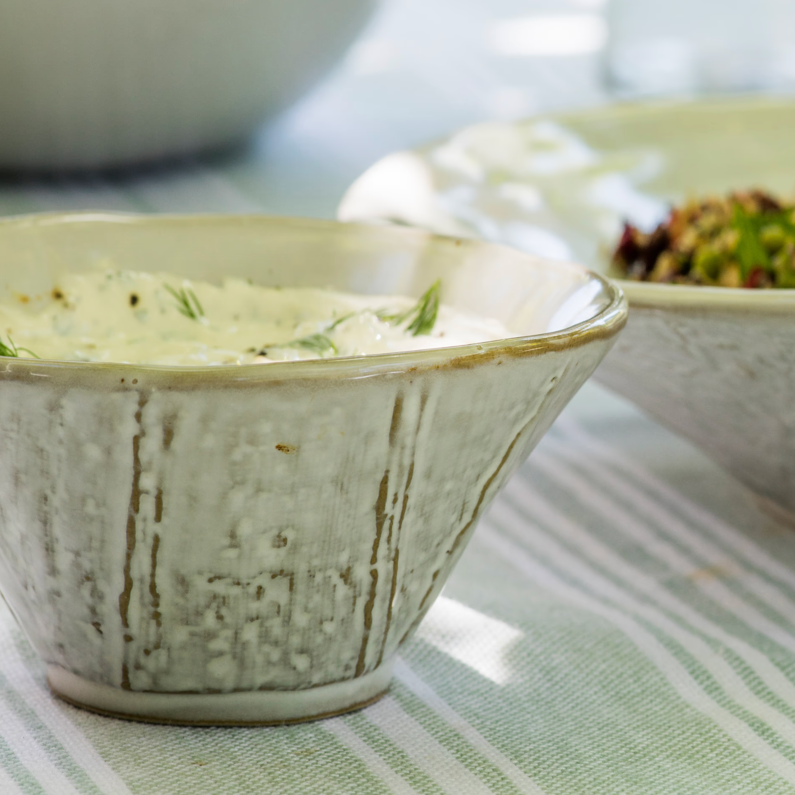 Rustic ceramic serving bowl on green table cloth.