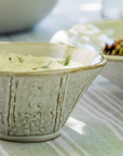 Rustic ceramic serving bowl on green table cloth.