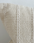 Close up of corner on cream bolster cushion with embroidered stripes.
