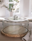 Recycled Glass Cake Dome with wooden base on wooden tale with gingham tea towel.