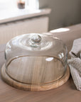 Recycled Glass Cake Dome with wooden base on wooden tale with gingham tea towel.