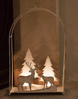 White reindeer forest scene hanging wall decor with lit tealights in, on a fireplace hearth.