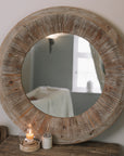 Rustic Round Wooden Mirror on wooden table with small candle and pot of matches.