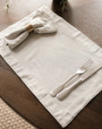 Charcoal and white pinstripe cotton placemat in dark table with cutlery and napkin in napkin ring.