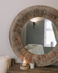 Rustic Round Wooden Mirror on wooden table with small candle and pot of matches.