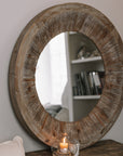 Rustic Round Wooden Mirror on wooden table with small candle and pot of matches.