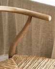 Close-up of a wooden wishbone dining chairs with wicker seat against a neutral background