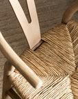 Close-up of a wooden wishbone dining chairs with woven seat and backrest.