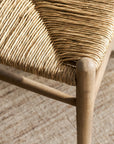 Close-up of a wicker wishbone dining chairs with wooden frame on a textured surface