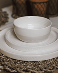 Set of cream crockery on a wicker place mat.