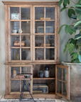 a large wooden armoire displaying books and decor items.