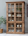 a wooden armoire displaying crockery and kitchen items.