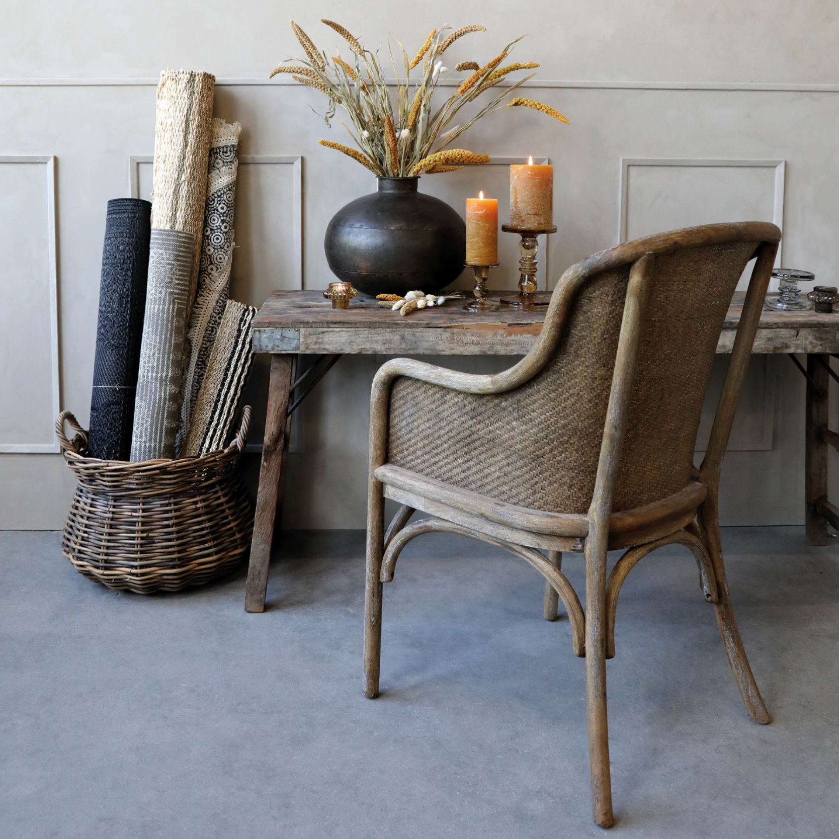 a rattan dining chair with a rustic console table and candles.
