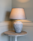 Grey Geometric Ceramic Lamp with Shade against panelled wall.