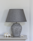 Grey Geometric Ceramic Lamp with Shade against panelled wall.