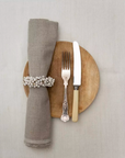 Wooden Napkin Ring with White Berries on a wooden plate with a knife and fork.