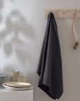 Dark grey kitchen towel hanging from wooden hook.