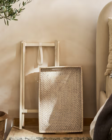 Rattan tray table folded up against a wall.