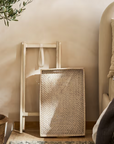 Rattan tray table folded up against a wall.