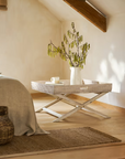 Rattan tray coffee table in bedroom with plant and mug on.
