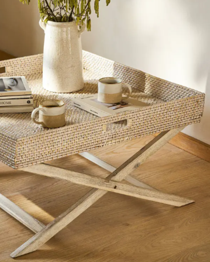 Close up of rattan tray coffee table in bedroom with plant and mug on.
