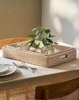 Rattan tray set stacked together on table with plant.