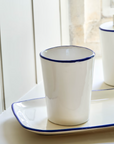 White and blue toothbrush holder on window sill.