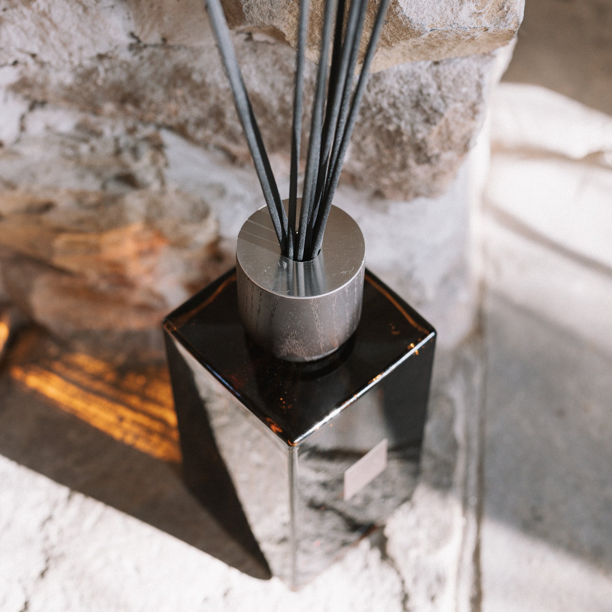 Large amber reed diffuser with presentation box on stone hearth.
