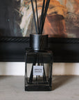 Sences Smoke Reed Diffuser against black painting.