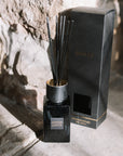 Sences alang alang reed diffuser with presentation box on stone hearth.