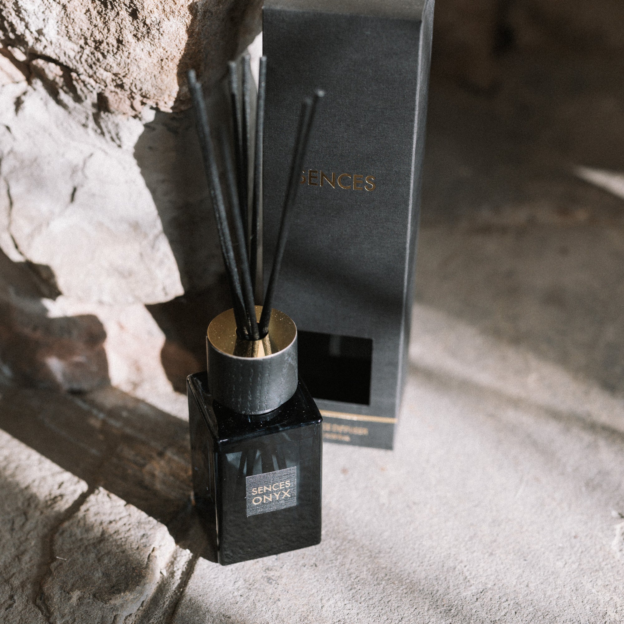 Sences alang alang reed diffuser with presentation box on stone hearth.