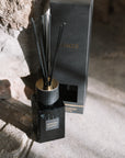 Sences alang alang reed diffuser with presentation box on stone hearth.