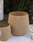 Set of two Jute Hurricane Lantern on linen and gingham table cloth outdoors.