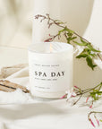 'Spa Day' soy candle on white background with flowers, wood and salt.